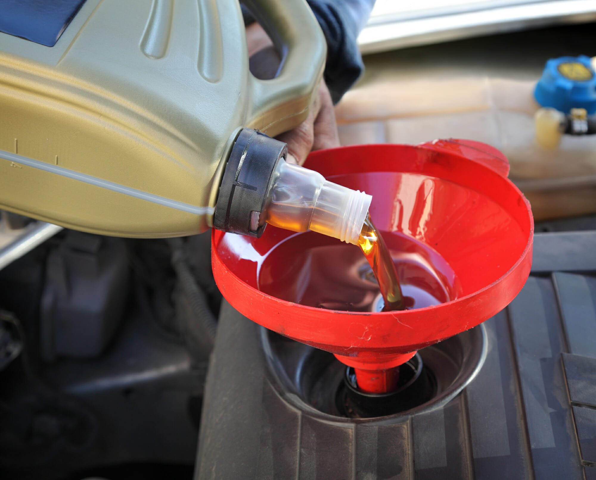 Auto Mechanic Pouring An Oil