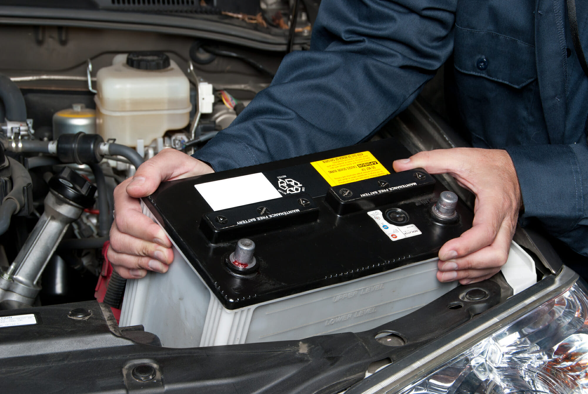A Car Mechanic Replacing A Battery