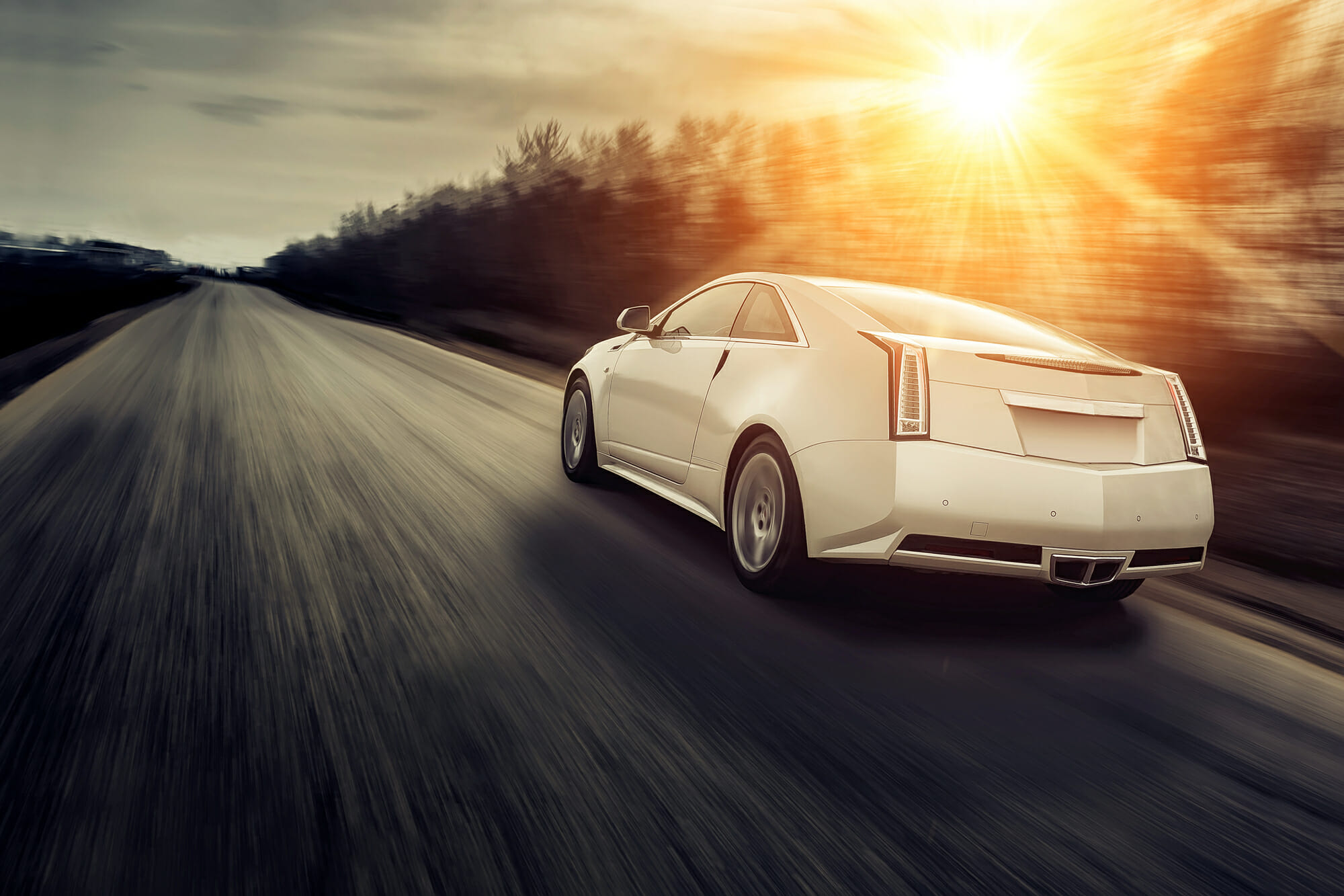 Cadillac car in motion with sun in background